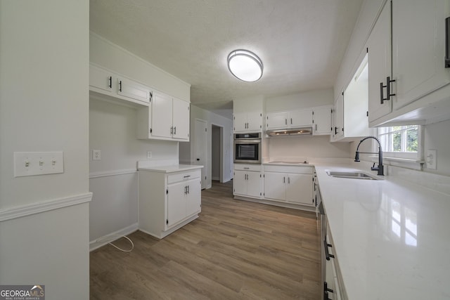 4732 Manly Ct, Stone Mountain, GA 30088 - kitchen with oven, white cabinetry, light wood-type flooring, a sink, and a textured ceiling