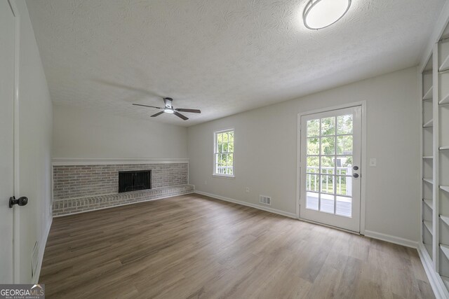 4732 Manly Ct, Stone Mountain, GA 30088 - unfurnished living room featuring a textured ceiling, ceiling fan, wood finished floors, a fireplace, and baseboards