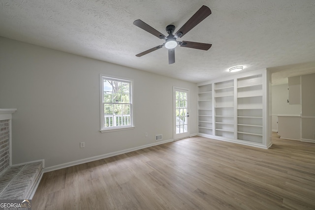 4732 Manly Ct, Stone Mountain, GA 30088 - unfurnished living room with a textured ceiling, ceiling fan, built in shelves, wood finished floors, and baseboards