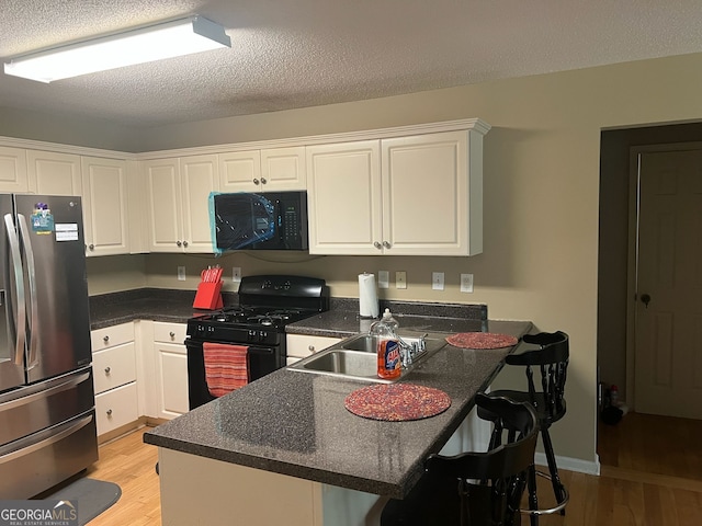 5327 Yoshino Ter, Powder Springs, GA 30127 - kitchen with black appliances, a peninsula, light wood finished floors, white cabinets, and a textured ceiling