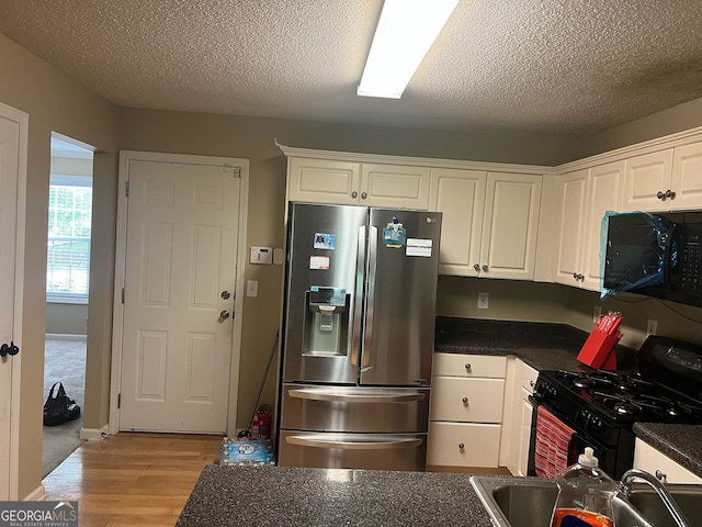 5327 Yoshino Ter, Powder Springs, GA 30127 - kitchen featuring black appliances, dark countertops, light wood-style floors, white cabinets, and a textured ceiling