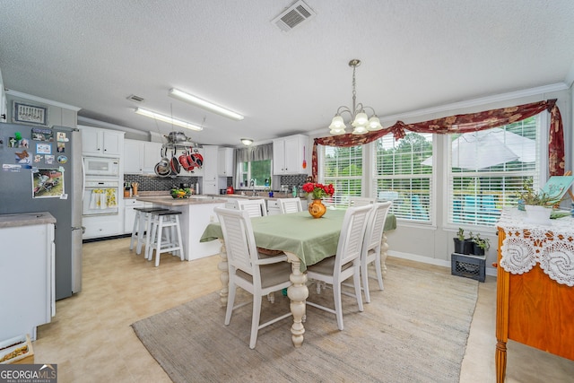 6162 Ayrin Brooke Ln, Blackshear, GA 31516 - dining area featuring a chandelier, a textured ceiling, light floors, and crown molding