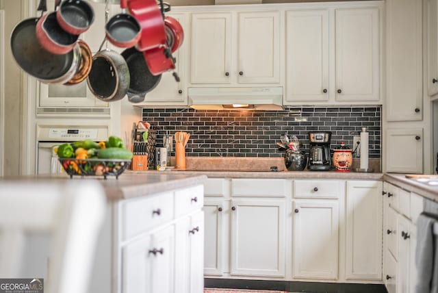 6162 Ayrin Brooke Ln, Blackshear, GA 31516 - kitchen with under cabinet range hood, light countertops, backsplash, white oven, and black electric cooktop