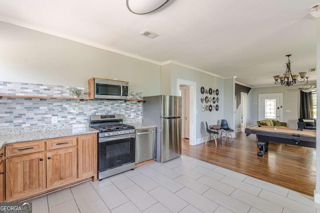 975 Dill Ave SW, Atlanta, GA 30310 - kitchen featuring stainless steel appliances, decorative backsplash, crown molding, light stone countertops, and a chandelier