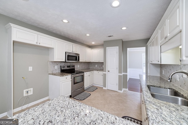 35 Deep Springs Way, Covington, GA 30016 - kitchen featuring appliances with stainless steel finishes, a sink, white cabinets, decorative backsplash, and light stone counters