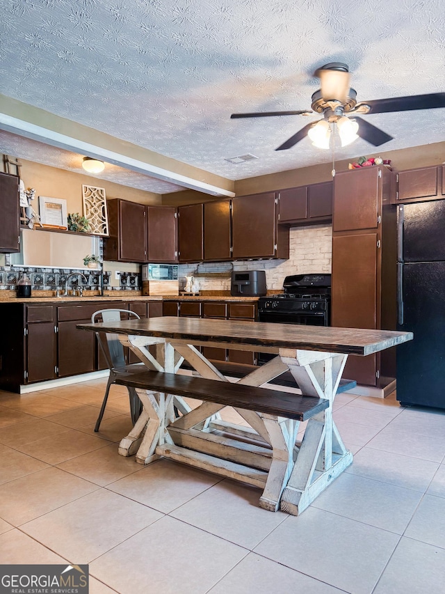 225 Second St, Bowdon, GA 30108 - kitchen with black appliances, a textured ceiling, dark brown cabinets, light tile patterned flooring, and a ceiling fan