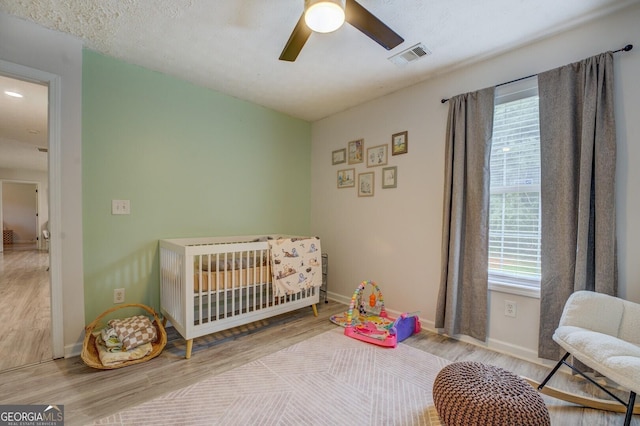 527 Malcom Rd, Covington, GA 30014 - bedroom featuring multiple windows, wood finished floors, a crib, and baseboards