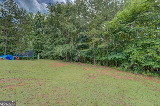 527 Malcom Rd, Covington, GA 30014 - view of grassy yard with a trampoline and a view of trees