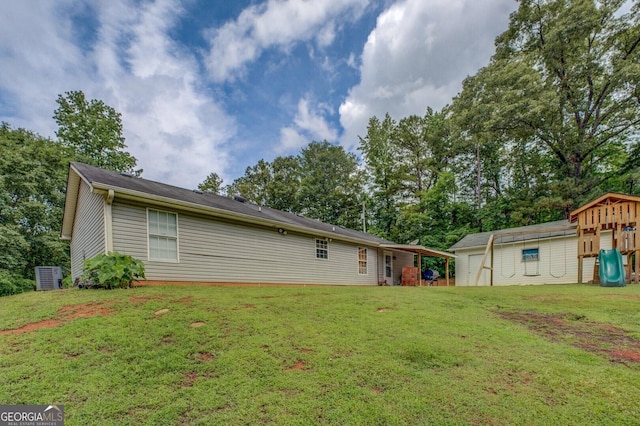 527 Malcom Rd, Covington, GA 30014 - back of house with a playground, a lawn, central air condition unit, an outbuilding, and view of scattered trees