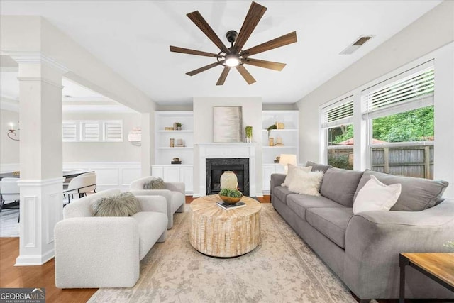 3607 Archgate Ct, Alpharetta, GA 30004 - living room with ornate columns, ceiling fan, wood finished floors, a high end fireplace, and a wainscoted wall