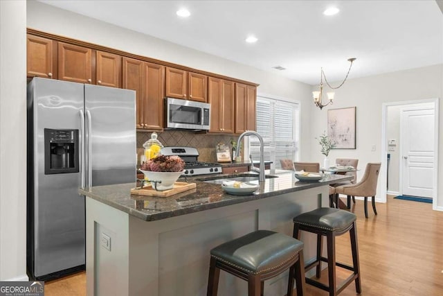 3607 Archgate Ct, Alpharetta, GA 30004 - kitchen featuring stainless steel appliances, brown cabinetry, backsplash, dark stone countertops, and a breakfast bar