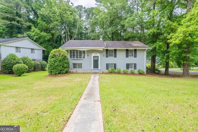 4669 Birch Ridge Trl, Stone Mountain, GA 30083 - raised ranch featuring a front lawn, brick siding, view of wooded area, and a shingled roof