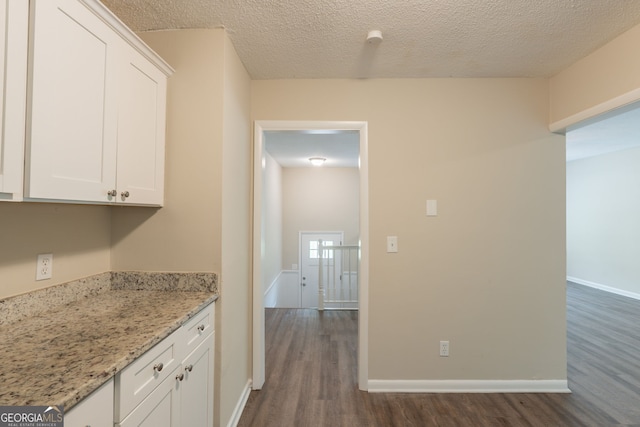 4669 Birch Ridge Trl, Stone Mountain, GA 30083 - kitchen with dark wood finished floors, white cabinetry, light stone countertops, and a textured ceiling