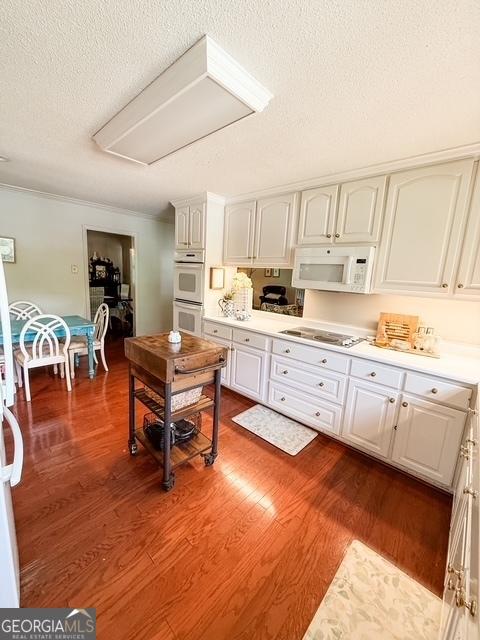 507 S College St, Metter, GA 30439 - kitchen with white appliances, white cabinetry, a textured ceiling, dark wood-style flooring, and light countertops