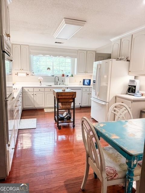 507 S College St, Metter, GA 30439 - kitchen with dark wood-style flooring, a textured ceiling, white appliances, a sink, and light countertops