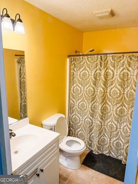317 S Terrell St, Metter, GA 30439 - bathroom featuring vanity, toilet, a textured ceiling, tile patterned floors, and a shower with curtain