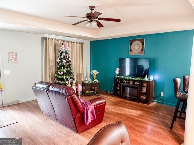 317 S Terrell St, Metter, GA 30439 - living area featuring wood finished floors, a glass covered fireplace, ceiling fan, and baseboards