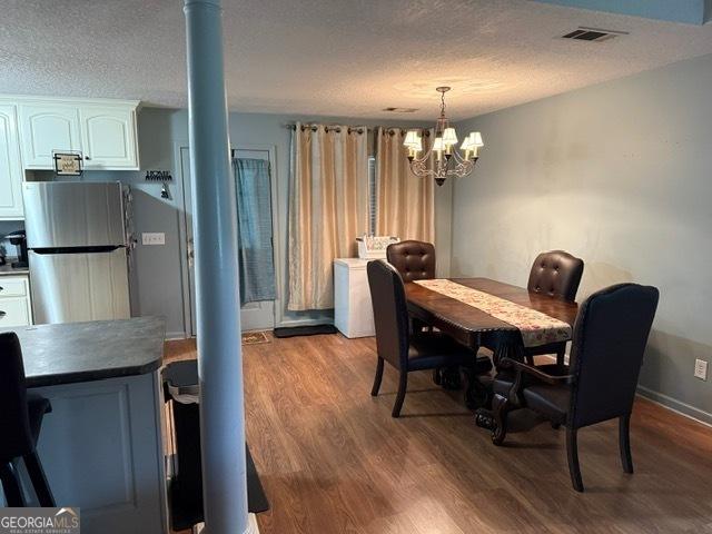 317 S Terrell St, Metter, GA 30439 - dining area featuring wood finished floors, a chandelier, decorative columns, and a textured ceiling