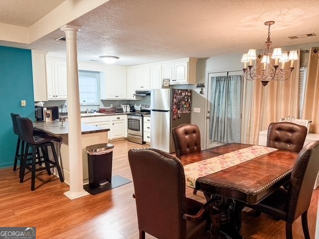 317 S Terrell St, Metter, GA 30439 - dining area featuring a chandelier, light wood-type flooring, a textured ceiling, and decorative columns