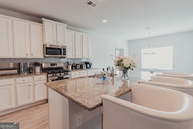 82 Castlemoor Loop, Adairsville, GA 30103 - kitchen with appliances with stainless steel finishes, backsplash, light wood-style flooring, light stone countertops, and white cabinetry