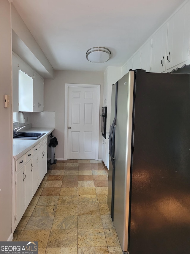4157 Cedar Valley Ln, Conley, GA 30288 - kitchen with stainless steel fridge, a sink, light countertops, white cabinets, and black oven