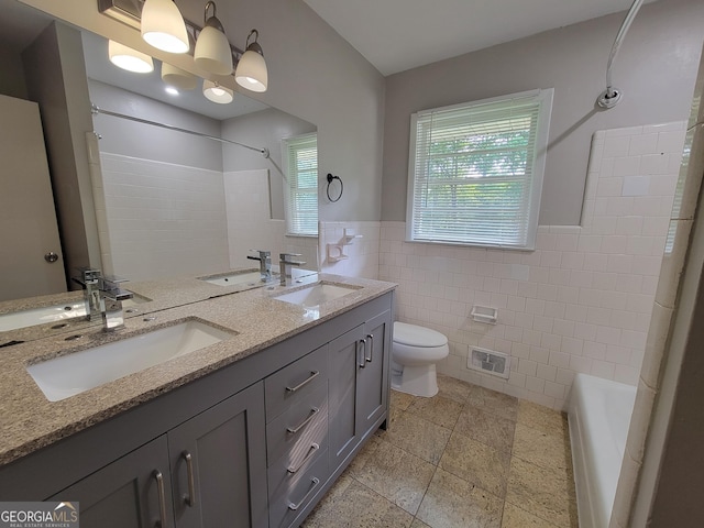 4157 Cedar Valley Ln, Conley, GA 30288 - bathroom with tile walls, double vanity, toilet, shower / washtub combination, and wainscoting