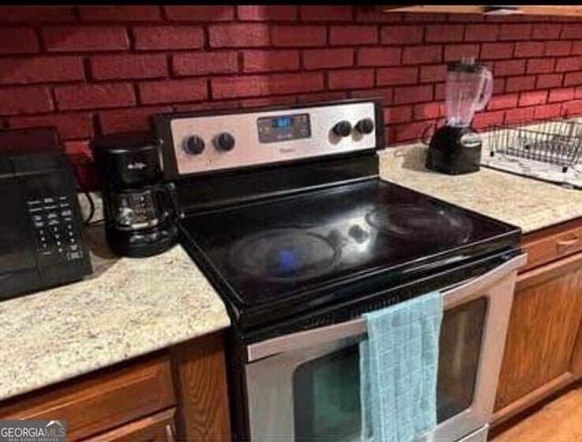 4157 Cedar Valley Ln, Conley, GA 30288 - kitchen featuring stainless steel range with electric stovetop, light countertops, and brick wall