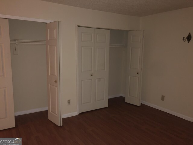 1308 Camelot Dr, South Fulton, GA 30349 - unfurnished bedroom with dark wood-type flooring, multiple closets, and a textured ceiling