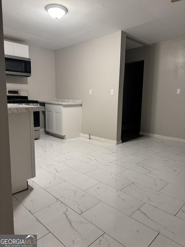 225 Bell St, Covington, GA 30016 - kitchen featuring appliances with stainless steel finishes, light marble finish flooring, and baseboards