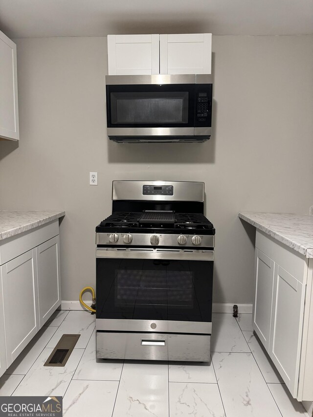 225 Bell St, Covington, GA 30016 - kitchen with appliances with stainless steel finishes, light marble finish flooring, and baseboards