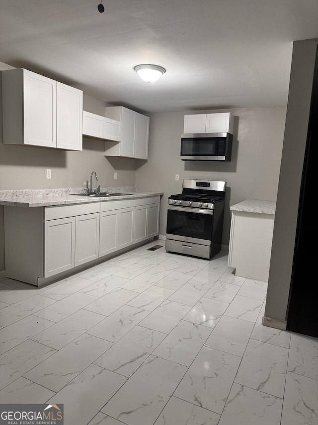 225 Bell St, Covington, GA 30016 - kitchen with stainless steel appliances, a sink, light marble finish floors, and light countertops