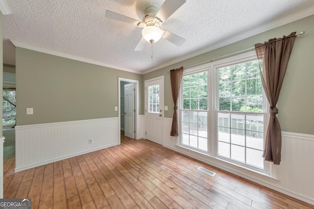 405 W Leslie Ct, Woodstock, GA 30188 - spare room with wainscoting, a textured ceiling, light wood finished floors, ceiling fan, and crown molding