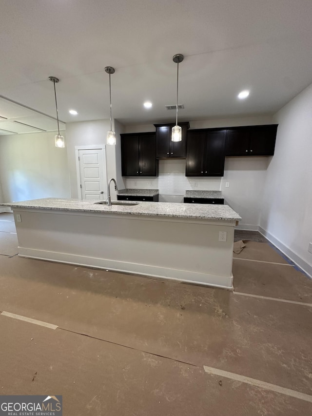 11156 Cornerstone Way, Hampton, GA 30228 - kitchen with dark cabinetry, light stone counters, concrete flooring, pendant lighting, and recessed lighting