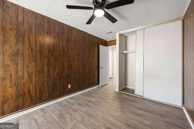 3184 Nectarine Cir, Decatur, GA 30034 - unfurnished bedroom featuring wood finished floors, ceiling fan, a closet, wooden walls, and a textured ceiling