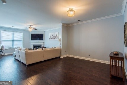 5535 Bright Cross Way, Suwanee, GA 30024 - living area with crown molding, a ceiling fan, dark wood-style flooring, and a fireplace