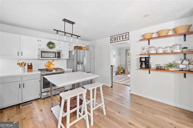150 Kensley Way, Dallas, GA 30157 - kitchen featuring stainless steel appliances, light wood-style flooring, light countertops, open shelves, and a textured ceiling