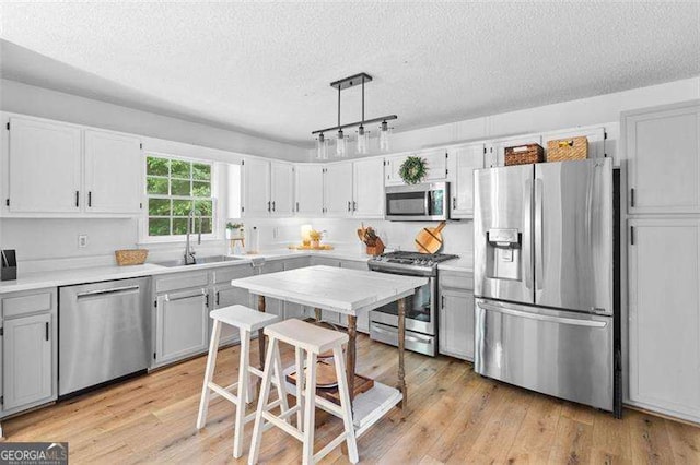 150 Kensley Way, Dallas, GA 30157 - kitchen with stainless steel appliances, a sink, a textured ceiling, light countertops, and light wood finished floors