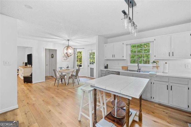 150 Kensley Way, Dallas, GA 30157 - kitchen with a textured ceiling, light countertops, light wood-style flooring, a chandelier, and a sink