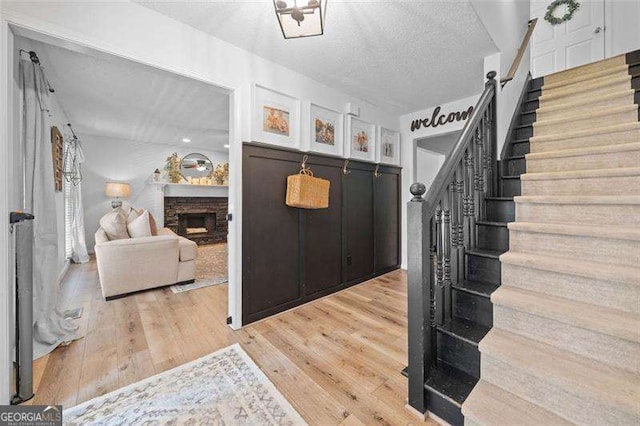 150 Kensley Way, Dallas, GA 30157 - mudroom featuring light wood-style flooring, a stone fireplace, and a textured ceiling