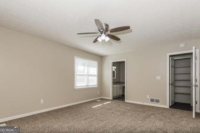 11102 Hunters Ln, Hampton, GA 30228 - unfurnished bedroom with dark carpet, ensuite bathroom, a ceiling fan, and a textured ceiling