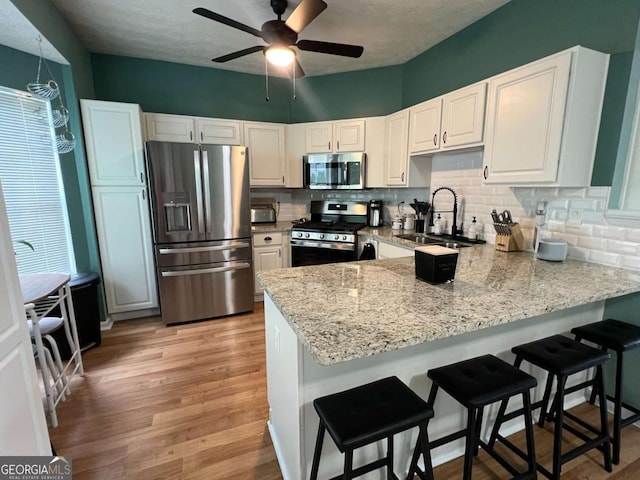 4336 Thorngate Ln, Acworth, GA 30101 - kitchen featuring stainless steel appliances, a peninsula, light stone countertops, and decorative backsplash