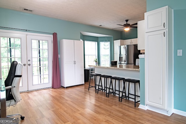 4336 Thorngate Ln, Acworth, GA 30101 - kitchen with stainless steel refrigerator with ice dispenser, a breakfast bar area, white cabinets, a peninsula, and ceiling fan
