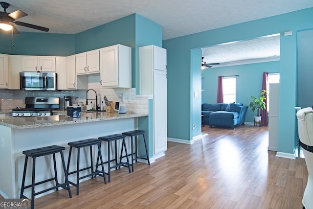4336 Thorngate Ln, Acworth, GA 30101 - kitchen with stainless steel appliances, a ceiling fan, decorative backsplash, white cabinets, and a textured ceiling