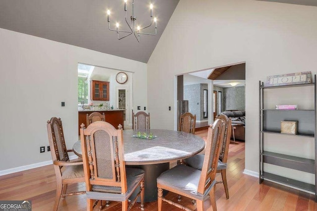 3493 Wood Acres Blvd, Duluth, GA 30096 - dining space with light wood finished floors, a chandelier, high vaulted ceiling, and baseboards