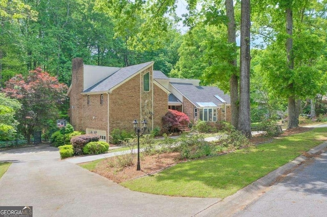 3493 Wood Acres Blvd, Duluth, GA 30096 - view of property exterior featuring a chimney, brick siding, driveway, and a lawn