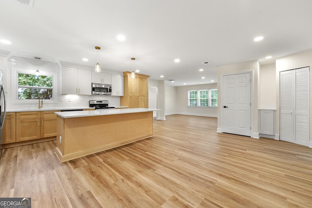 381 Warner St SE, Marietta, GA 30060 - kitchen featuring stainless steel appliances, light countertops, light wood-style floors, recessed lighting, and a center island