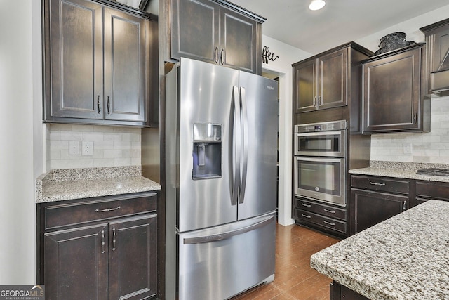 819 Firefly Ct, Griffin, GA 30223 - kitchen featuring appliances with stainless steel finishes, backsplash, dark brown cabinets, dark wood-style flooring, and light stone counters