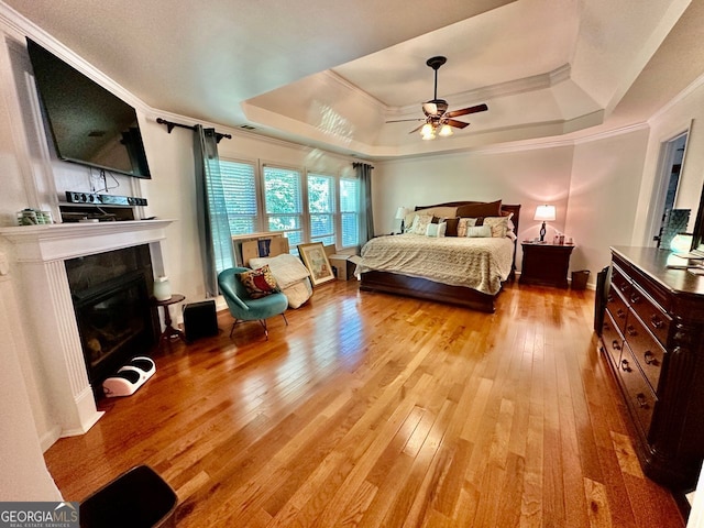4265 Lansmoore, Suwanee, GA 30024 - bedroom featuring a raised ceiling, light wood-style floors, ornamental molding, a glass covered fireplace, and ceiling fan