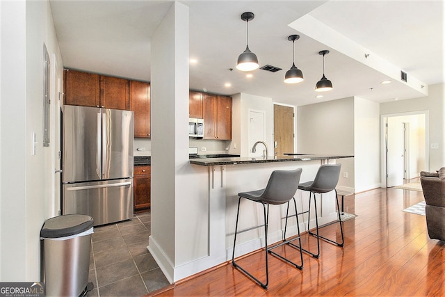 171 Auburn Ave NE Unit 521, Atlanta, GA 30303 - kitchen featuring appliances with stainless steel finishes, brown cabinets, dark countertops, a kitchen breakfast bar, and a peninsula