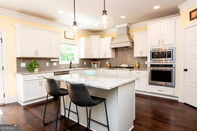 1032 Switchgrass Dr, Statham, GA 30666 - kitchen with stainless steel appliances, custom exhaust hood, a kitchen breakfast bar, a kitchen island, and white cabinets